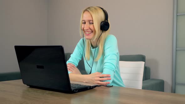 Female Freelancer with Headphones is Talking in Video Chat Using Laptop