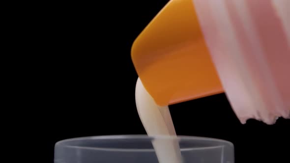 Pouring laundry detergent into the measuring cap from a plastic bottle