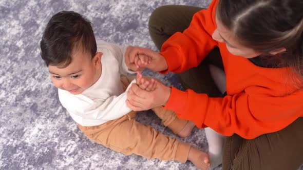 Mother holding baby's hands.