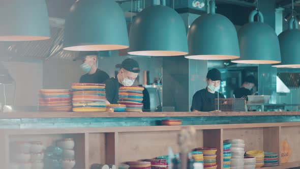 Restaurant Counter with Cooking Staff in Face Masks Behind It