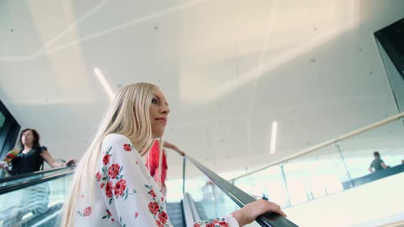 Young Blonde Woman Riding on Escalator.