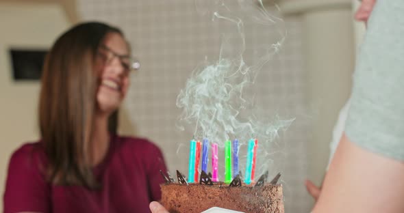 Young Pretty Woman is Making Wish and Blowing Out Candles on Birthday Cake While Celebrating