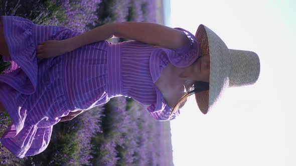 Woman in a Short Purple Dress and a Hat Stands on a Lavender Field