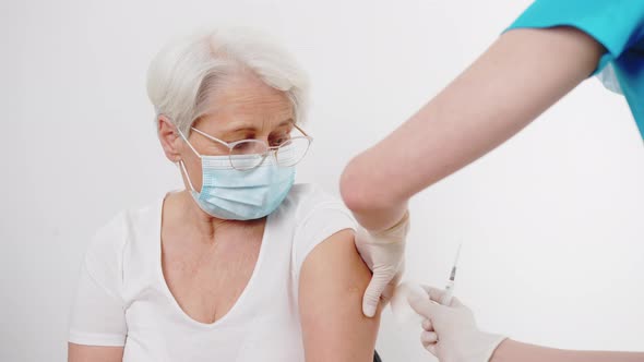 Doctor Disinfecting Senior Woman's Arm Before Vaccination Medium Closeup White Background Indoors