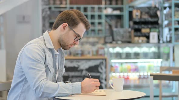 Man Writing on Notebook Thinking