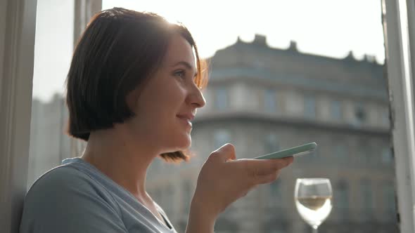 Portrait of Smiling Woman Using Smartphone Voice Recognition