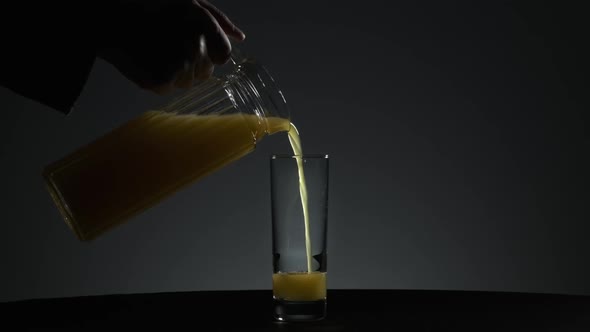 Orange Juice is Poured Into a Glass on a Neutral Background