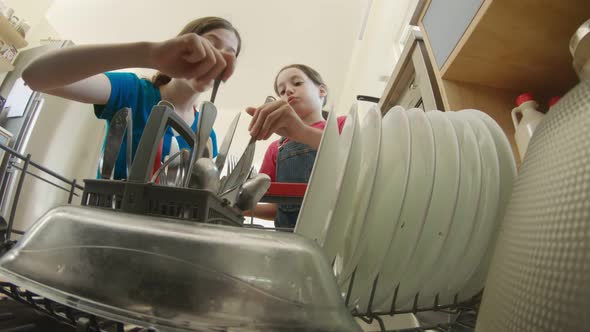 Two girls fill the dishwasher with dirty dishes