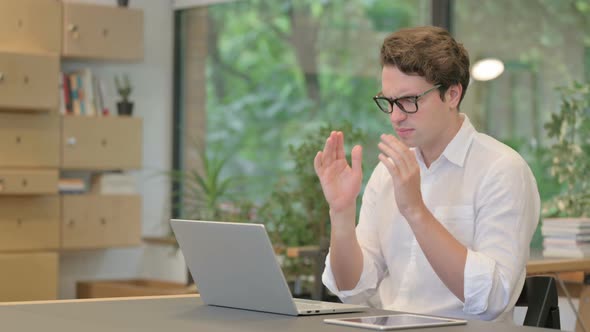 Young Man Having Headache While Working on Laptop in Modern Office