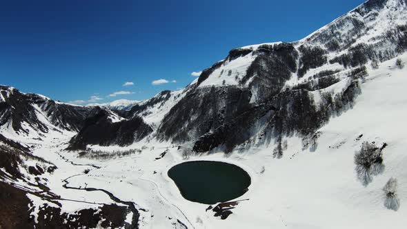 Paraglider Coming Down Against the Background of the Beautiful Lake and the Snowcovered Hills