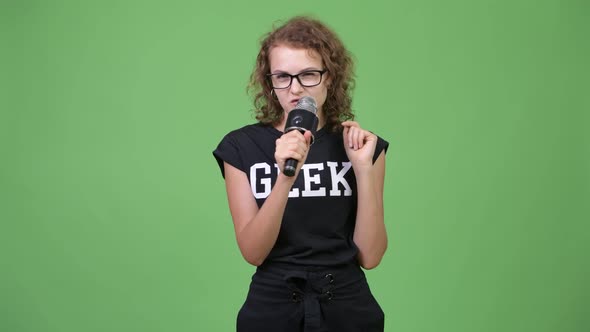 Young Happy Beautiful Nerd Woman Presenting Something with Microphone