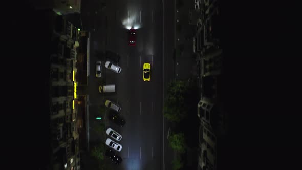 A beautiful sports car drives at night along modern city streets among skyscrapers and houses. 