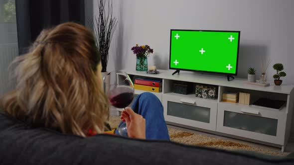 Woman watching Tv Green Chroma Key Screen and Drink wine.