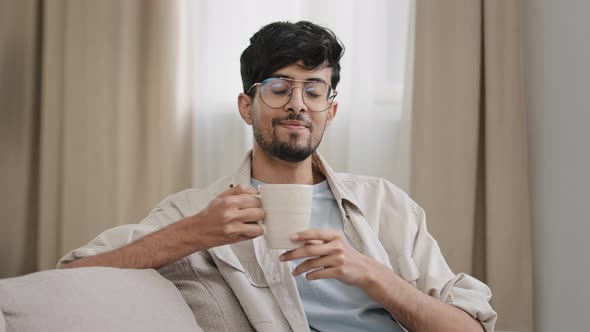 Arabic Bearded Millennial Man Latin Guy in Glasses Sitting at Home Enjoying Delicious Hot Fruit