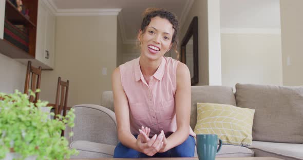 Happy biracial woman sitting on sofa and having video call