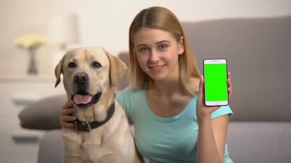 Happy Woman Hugging Cute Labrador Dog, Showing Green Screen Smartphone, Pet App
