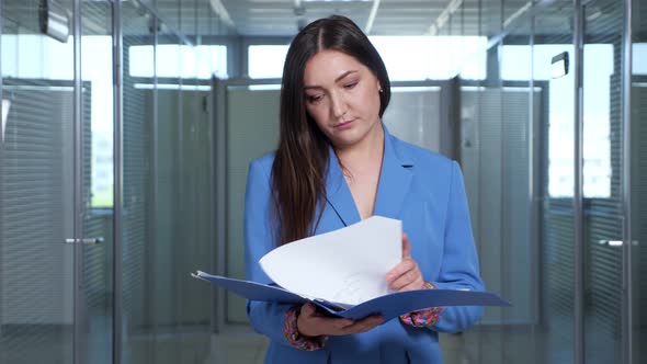 Concentrated Brunette Businesswoman Looks Through Reports