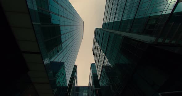 Low Angle of the Facades of Skyscrapers with Clouds and Blue Sky in Reflection