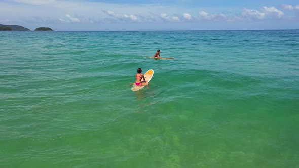 4K Aerial view group of Asian woman surfing in the sea at tropical beach.