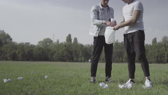 Young Millennial Volunteers Gathering Garbage on Green Summer Meadow