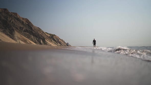 Man Walking Along Beach As Tide Comes In