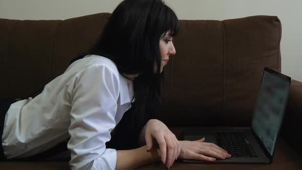 Young Woman Using Laptop at Home Sitting on Sofa