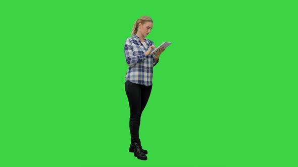 Young Woman Standing on Green Background with Digital Tablet on a Green Screen