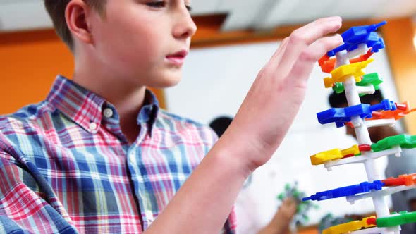 Schoolboy experimenting molecule model in laboratory at school