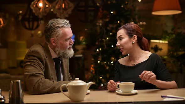 a man and a woman chat and drink tea at the bar in a restaurant