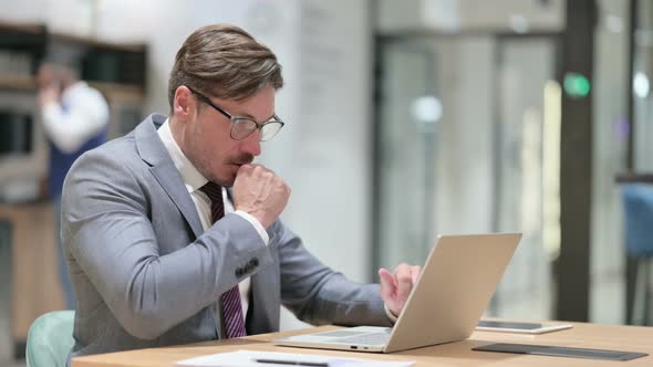 Sick Businessman with Laptop Coughing in Office 