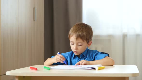 A Charming Boy Spends His Time Drawing with Colored Pencils While Sitting at a Table, Lifestyle