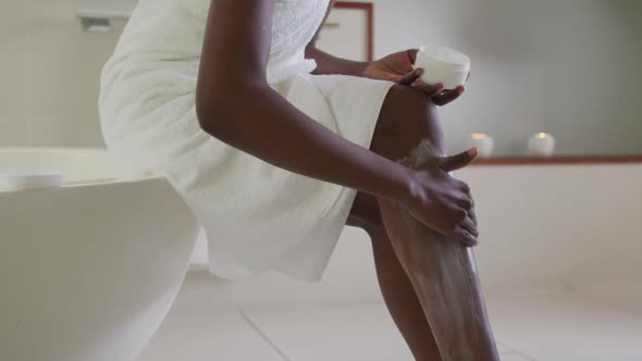 African american attractive woman applying body balm in bathroom