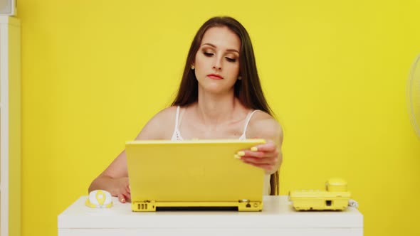 Young Woman Uses Yellow Laptop