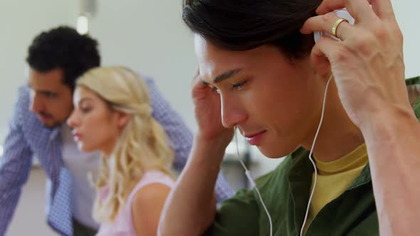 Happy executive listening music on headphones at desk 4k