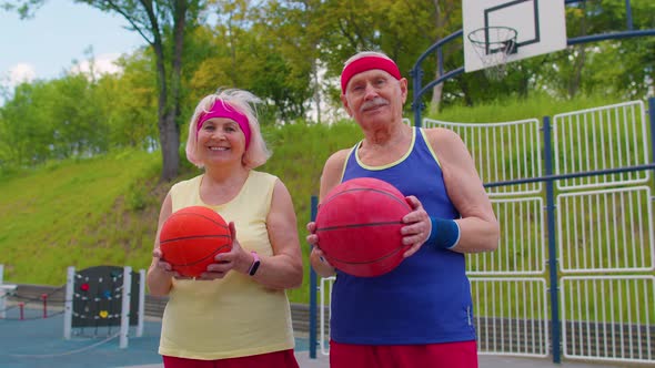 Active Senior Basketball Team Man Woman Playing Game with Ball Smiling Looking at Camera at Stadium