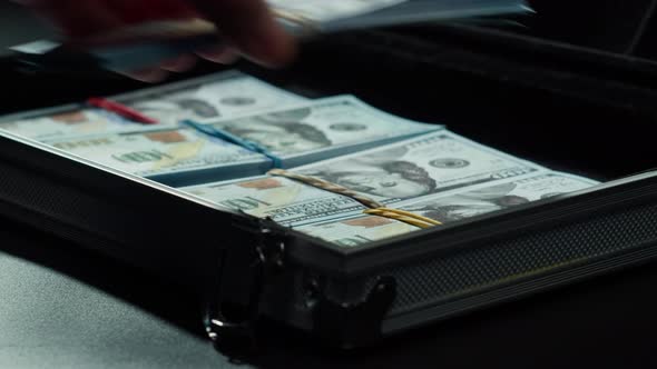 Counting American Hundred Dollar Banknotes Putting Money in Metallic Suitcase