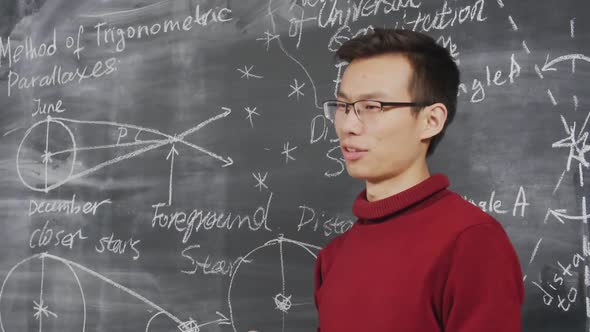 Young Asian Man Speaking at Blackboard