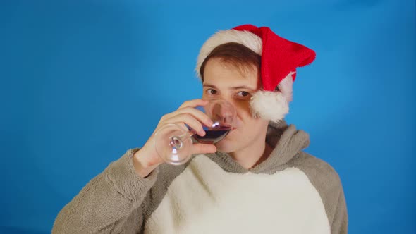 Happy Man in Santa Hat with Alcohol on Blue Background