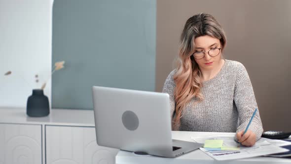 Focused Woman Writing Paperwork e Learning Use Laptop Pc in Home Office