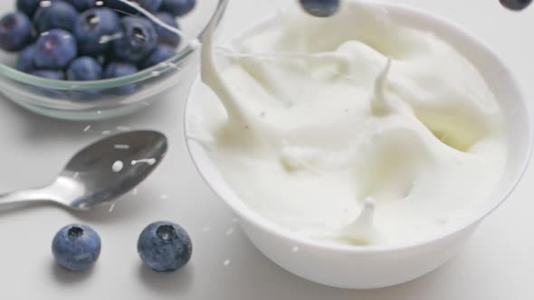 Blueberries falling in thick greek yogurt. Slow motion. Healthy food concept