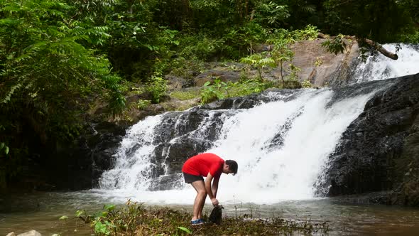 Traveler Man Enjoying Waterfall Open Waterproof Bag and Take Mobile Phone