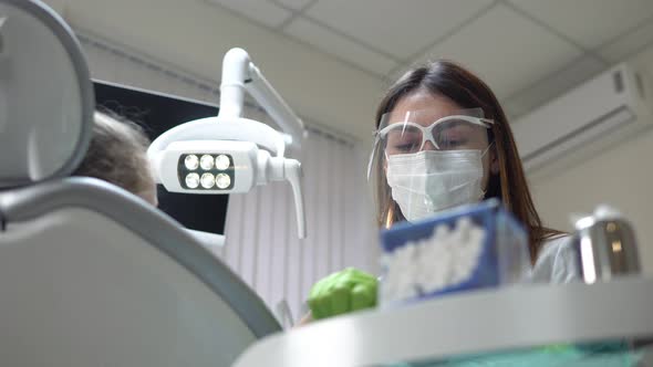 Friendly Female Dentist Turning on the Lights and Taking Her Instruments Before Doing Routine Check