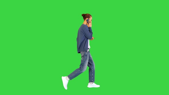 Young White Man Walks Talking on Mobile Phone on a Green Screen Chroma Key