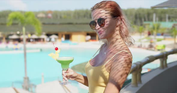 Stylish Woman with Green Beverage on Hotel Terrace