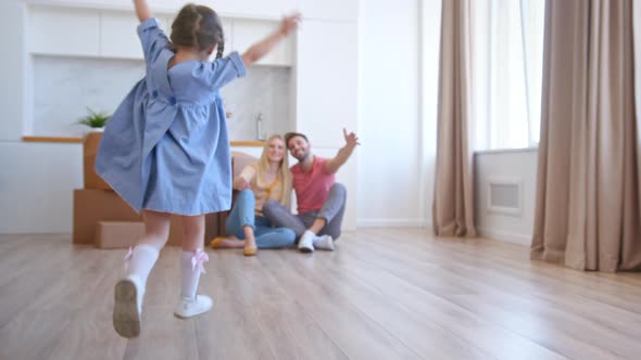 Happy preschooler girl in blue dress runs to parents