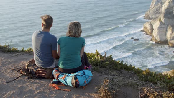 Couple of Backpackers Taking Break Sitting at Cliff