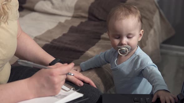 Self-isolation of family life. Mom works at home with a laptop, distracted by her child.