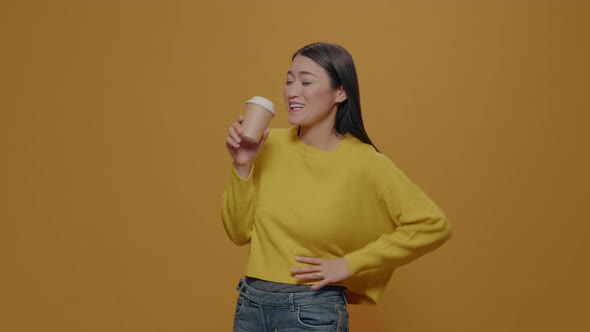 Asian Woman Drinking Coffee From Cup in Front of Camera