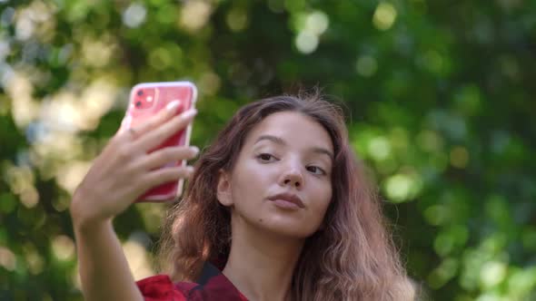 Fashionable Young Woman in Checkered Shirt Fixes Curly Hair