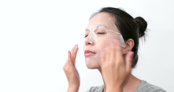 Woman apply paper mask sheet on face 